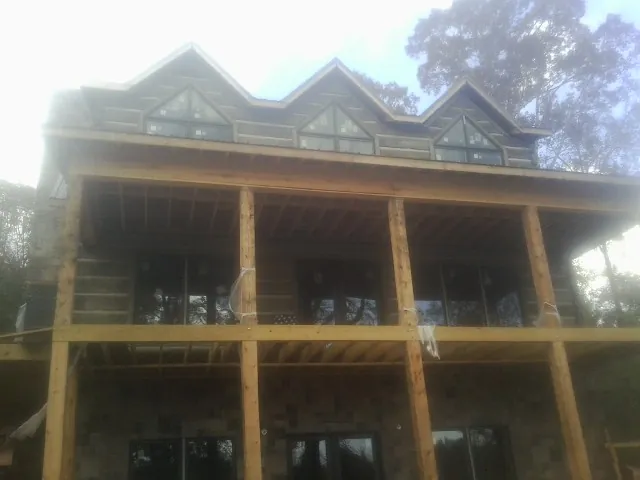 Dormers and porch framing on a large log home under construction — Roof Coating work by our crew in Riverside